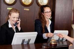 Recepcionista de hotel entregando cartão de acesso a hóspede no balcão da recepção