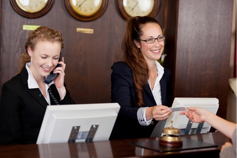 Recepcionista de hotel entregando cartão de acesso a hóspede no balcão da recepção